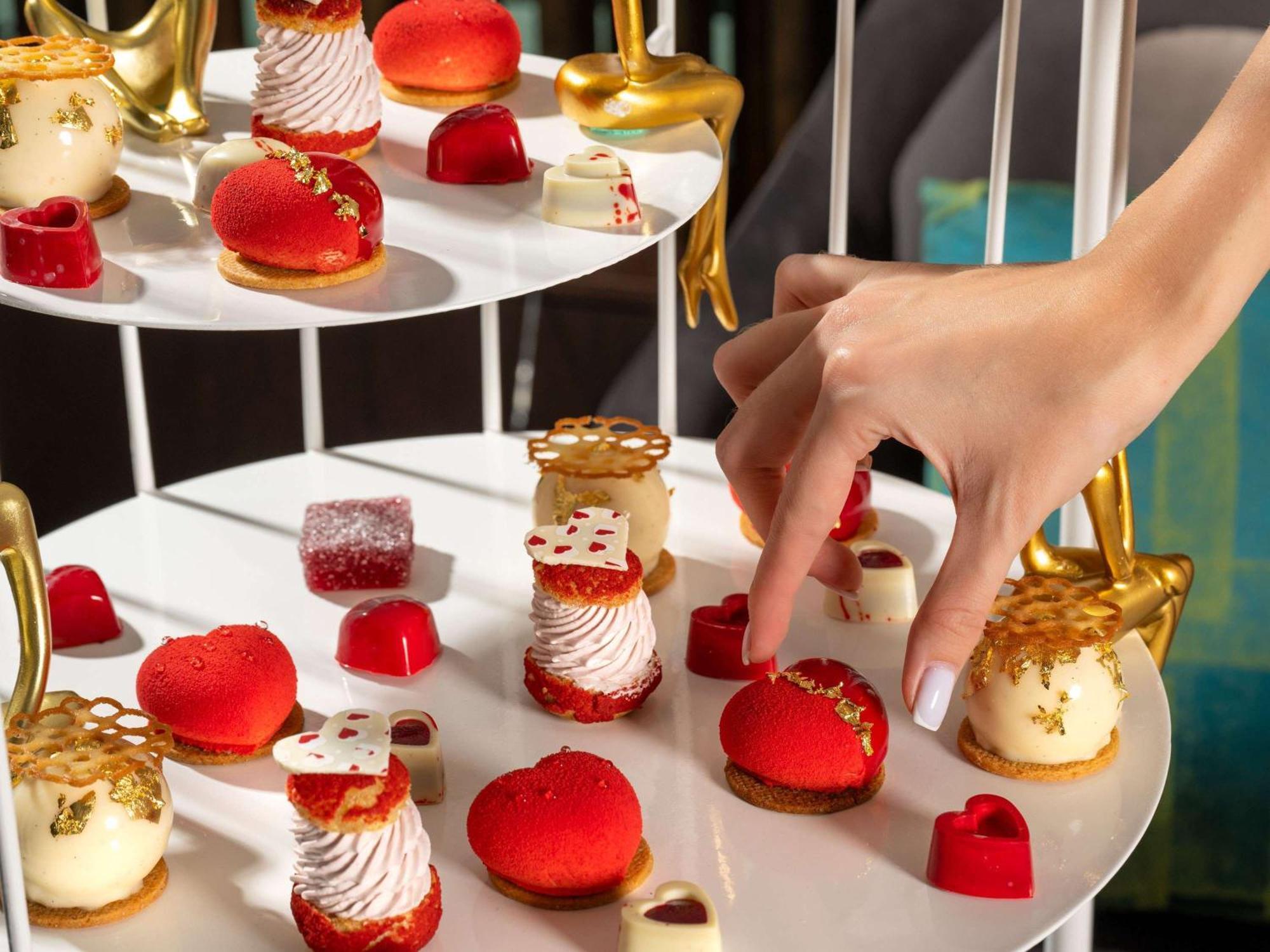 Sofitel Dubai Downtown Hotel Kültér fotó A hand selecting a dessert from a tiered platter